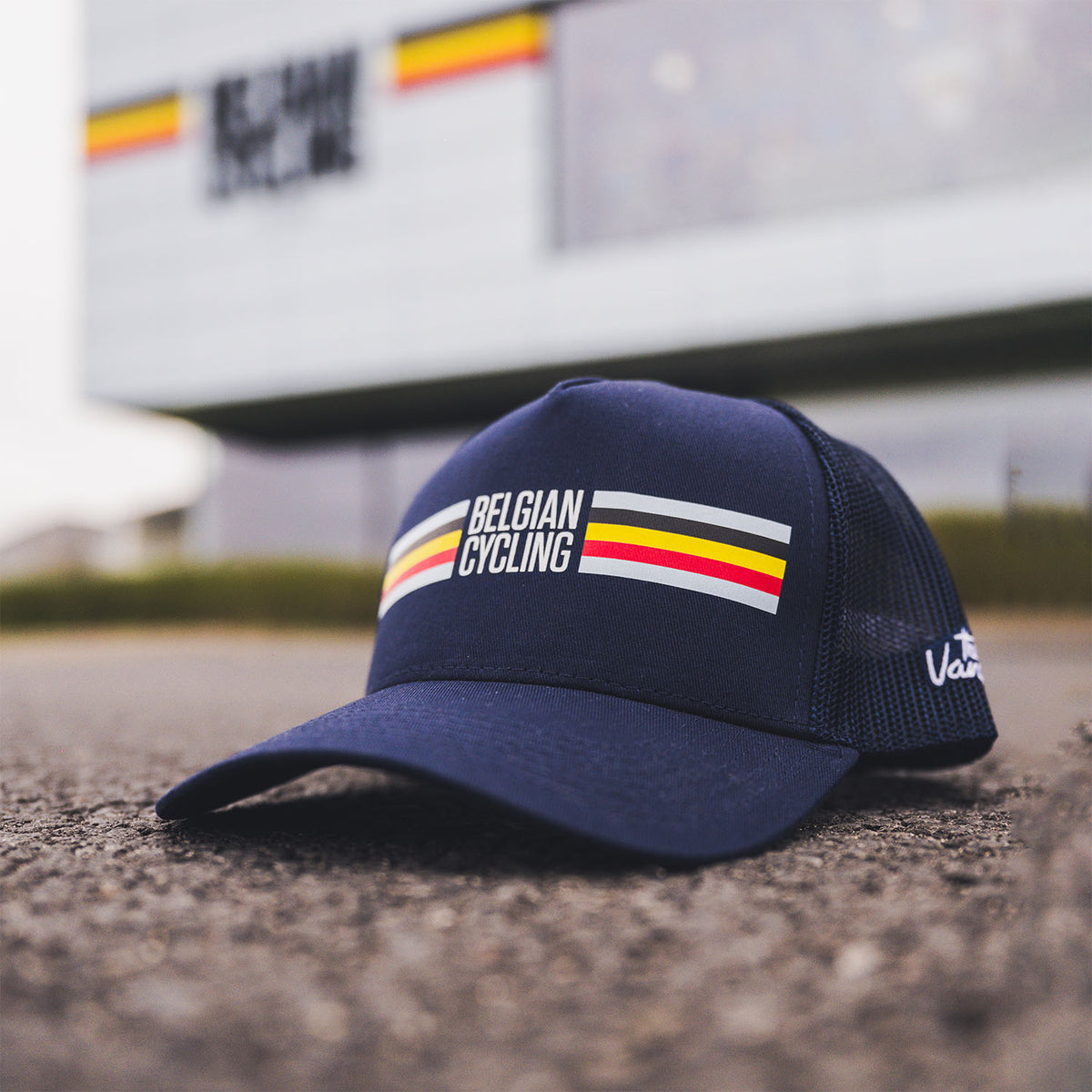 Navy blue Belgian Cycling cap with black mesh and Belgian flag stripes, photographed in front of the Belgian Cycling Center