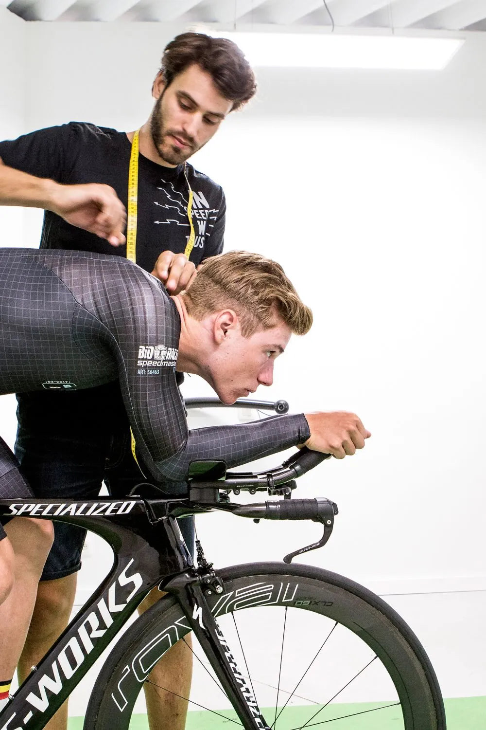 Remco Evenepoel in aerodynamic fitting session on a time trial bike, assisted by a Bioracer technician during individual speedwear calibration.