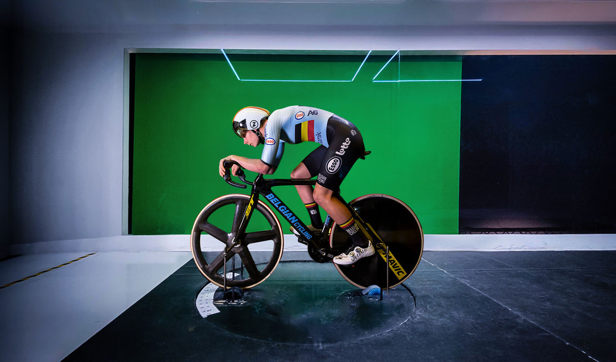 Lotte Kopecky in Belgian national team kit during aerodynamic testing on track bike in wind tunnel with green screen background.